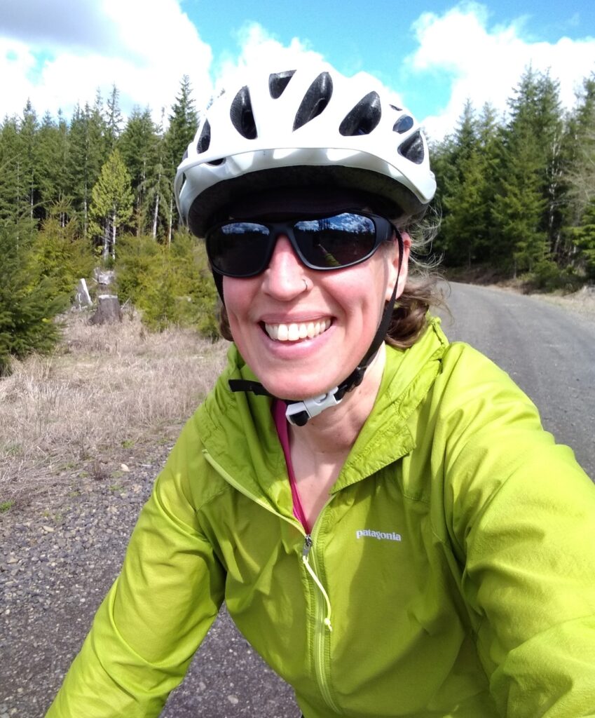 Sarah wearing a helmet and sunglasses while cycling on a gravel road